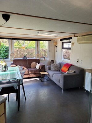 En moderne stue med et glasbord, to sofaer og et stort vindue med udsigt til naturen.
