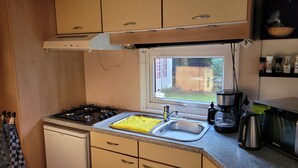 Una cucina compatta con piano cottura a gas, lavandino e finestra.