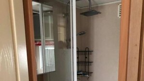 Un bagno compatto con doccia, lavandino e specchio.