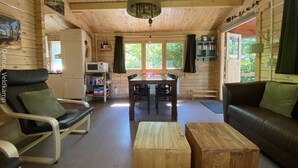 A wooden cabin interior with a dining table, chairs, a sofa, and a wooden coffee table. - Tranquility and Natural Beauty Await at Our Secluded Finnish Chalet (Epe)