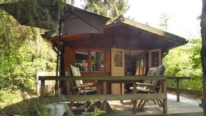 A wooden cabin with a deck, two chairs, and a table. - Tranquility and Natural Beauty Await at Our Secluded Finnish Chalet (Epe)