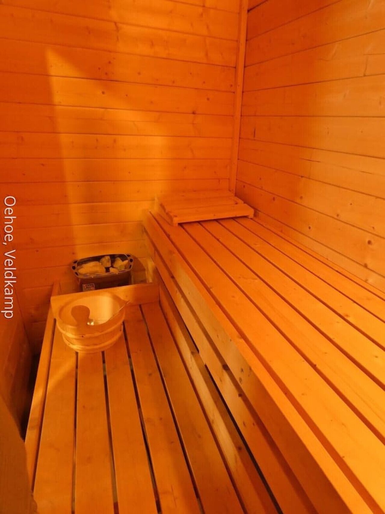 A sauna room with wooden benches and a small table with a bowl.
