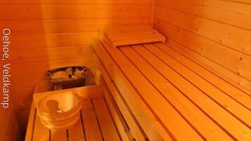 A sauna room with wooden benches and a small table with a bowl.