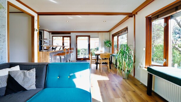 Un salon moderne avec un canapé bleu, un plancher en bois et de grandes fenêtres.