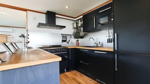 Une cuisine moderne avec des meubles de couleur noire, un plan de travail en bois, une cuisinière, un four à micro-ondes et un réfrigérateur.