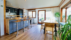 Une cuisine moderne avec un coin bar, un plancher en bois et de grandes fenêtres.