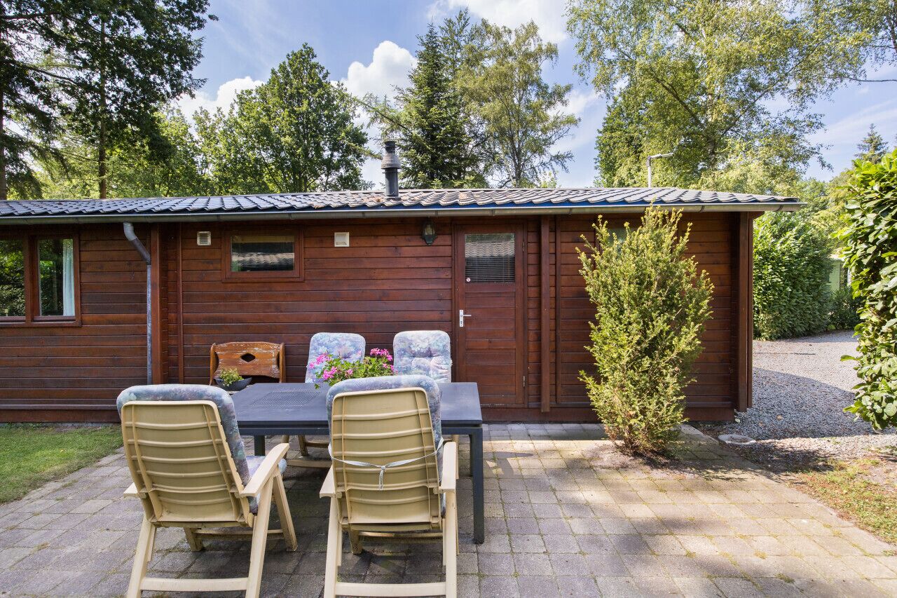Eine Holzhütte mit Ziegeldach, einem Esstisch mit zwei Stühlen und einem kleinen Garten.