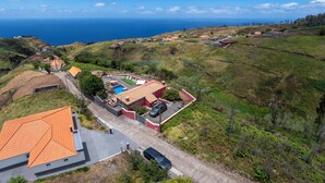 A residential area with houses, a swimming pool, and a view of the ocean. - With pool and barbecue - Villa Roque (Ponta do Pargo)