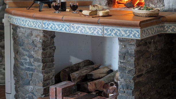 A stone fireplace with a wood-burning stove, a wine bottle, and a bowl on the mantel. - With pool and barbecue - Villa Roque (Ponta do Pargo)