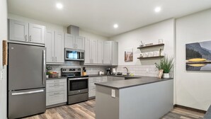 A modern kitchen with grey cabinets, stainless steel appliances, a central island, and a wooden herringbone floor. - No Cleaning Fee!! King Sized Bed!!Nature All Around!! (Bighorn No. 8)