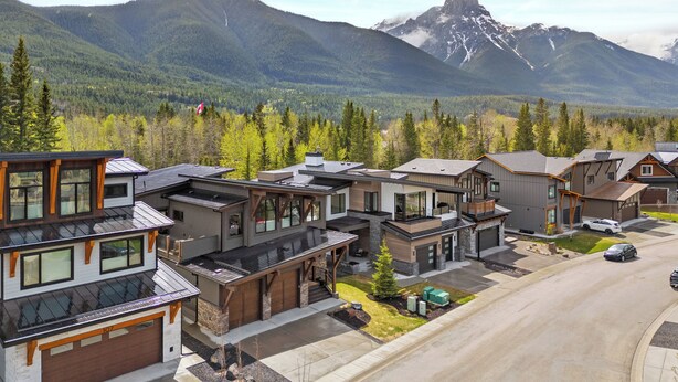A modern residential area with houses featuring large windows and a mix of architectural styles, set against a backdrop of mountains and forested hills. - No Cleaning Fee!! King Sized Bed!!Nature All Around!! (Bighorn No. 8)