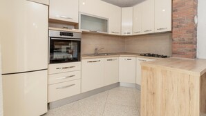 A modern kitchen with white cabinets, a built-in oven, a sink, and a wooden countertop. - 2 bedroom beautiful apartment in Sveti Juraj (Sveti Juraj)