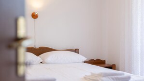 A neatly made bed with white linens and pillows, a wooden headboard, and a bedside table with a lamp. - 2 bedroom beautiful apartment in Sveti Juraj (Sveti Juraj)