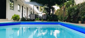 A swimming pool with blue tiles, surrounded by potted plants and outdoor furniture. - Hotel Bremen (Tapachula)
