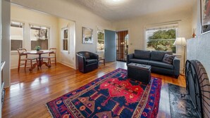 A spacious living room with hardwood flooring, a large rug, a sofa, a coffee table, and a fireplace. - Charming / Outdoor Dining / 1 BR 1 BA / Sam Hughes (Tucson)