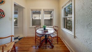 A dining area with a wooden table and chairs, a potted plant, and a view through a window. - Charming / Outdoor Dining / 1 BR 1 BA / Sam Hughes (Tucson)