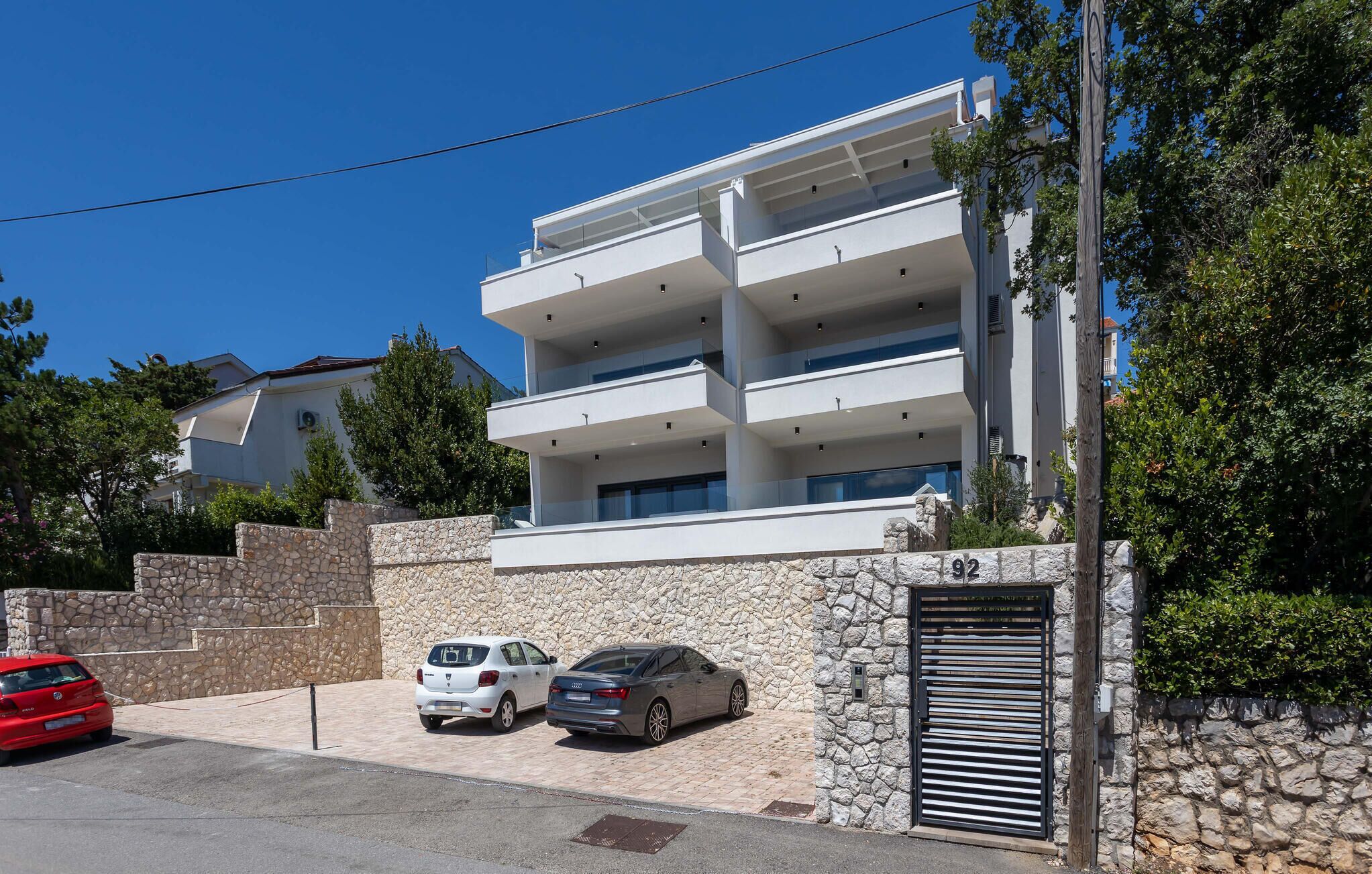 Un immeuble résidentiel moderne à plusieurs étages, doté d’une façade en pierre et d’une entrée sécurisée par un portail.