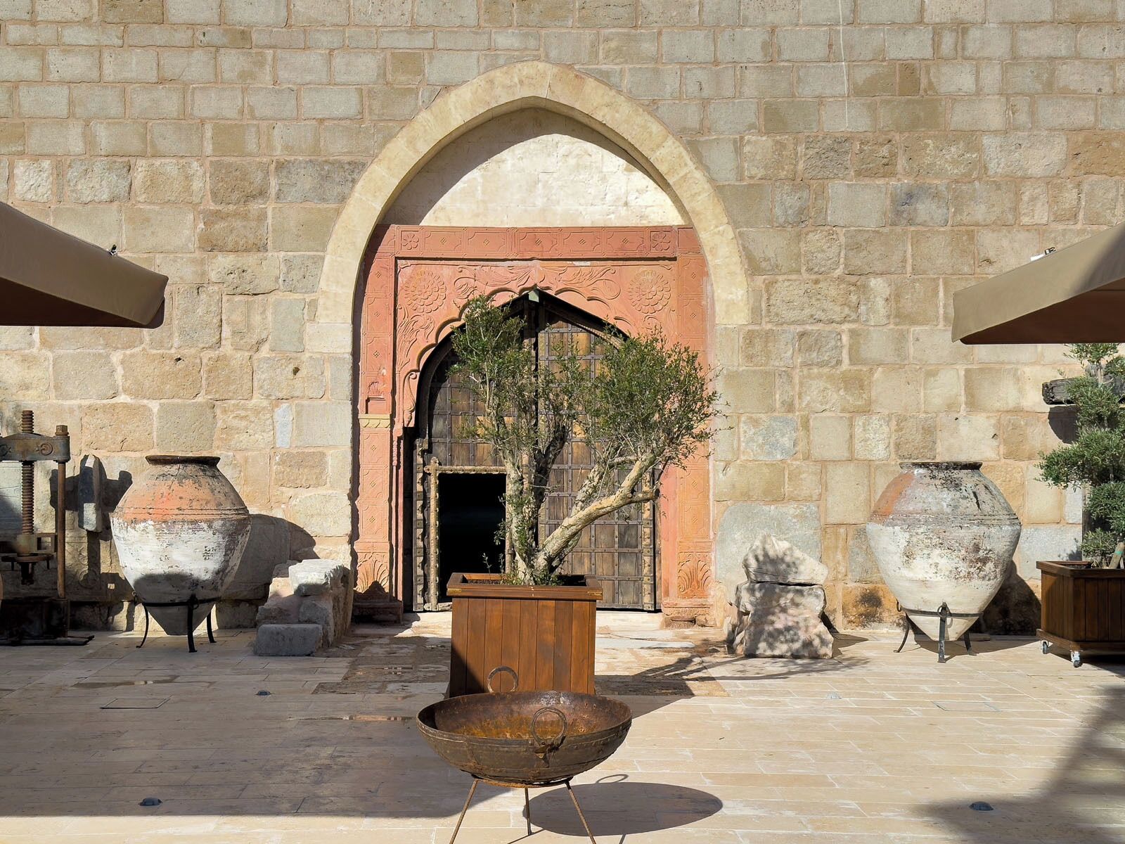 Un patio al aire libre con muros de piedra, una puerta de madera y varios jarrones grandes.