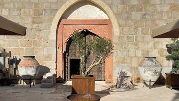 Un patio al aire libre con muros de piedra, una puerta de madera y varios jarrones grandes.