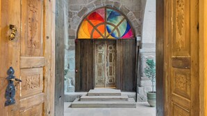 A wooden door with intricate carvings, leading to a stone archway with a colorful stained glass window above a wooden door. - Obruk Kervansaray Museum Hotel (Konya)