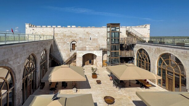 A courtyard with stone walls, arched windows, and outdoor seating areas. - Obruk Kervansaray Museum Hotel (Konya)