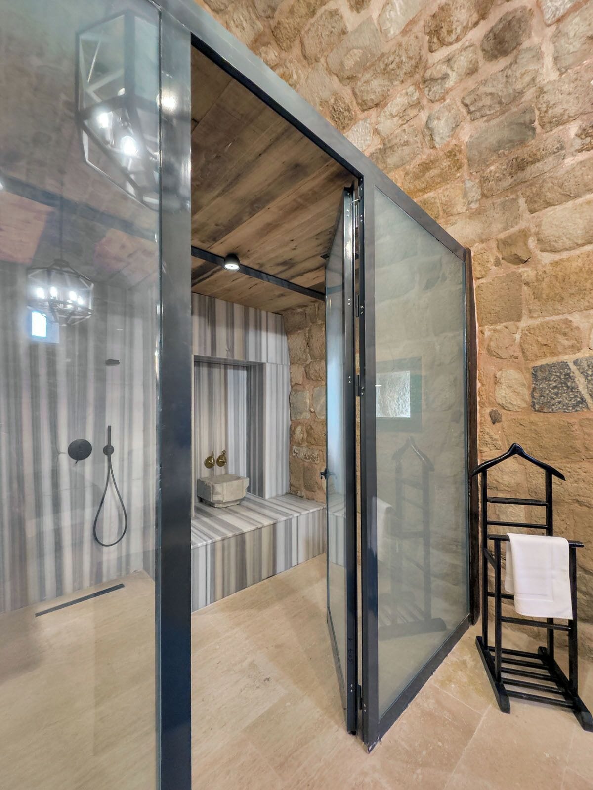 Un bagno moderno con box doccia in vetro, parete in pietra e design minimalista.