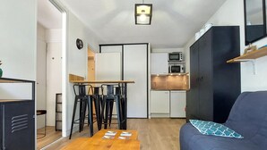 A compact living space with a kitchenette, a dining area with chairs, a sofa, and a wooden coffee table. - 1 bedroom nice apartment in Carnac (Carnac)