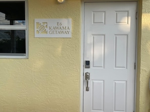 Une porte sur laquelle est affichée une pancarte indiquant : « E6 KAWAMA GETAWAY ».