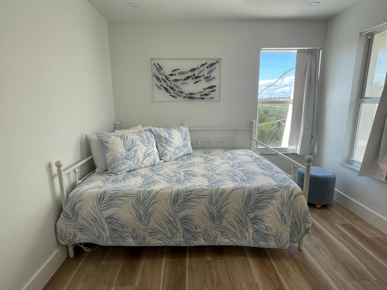 Un dormitorio con cama, ventana y una obra de arte colgada en la pared.