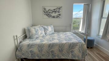 Un dormitorio con cama, ventana y una obra de arte colgada en la pared.