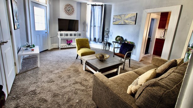 A living room with a sofa, armchair, coffee table, TV, and a ceiling fan.