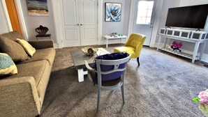 A living room with a grey sofa, a yellow armchair, a coffee table, and a TV stand with a flat-screen TV.