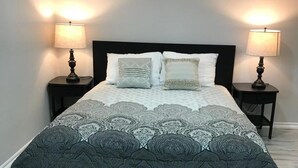 Une chambre à coucher avec un grand lit, deux tables de chevet et deux lampes fixées au mur.