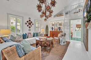 A spacious living room with a high ceiling, a decorative star chandelier, and a view of the outdoors through large windows. - The Pink House in Virginia Beach (Virginia Beach)