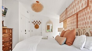 Un dormitorio con una cama grande, cómoda de madera y un espejo decorativo.