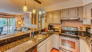 A modern kitchen with granite countertops, stainless steel appliances, and pendant lighting. - Riverfront Oasis at Loon (Lincoln)