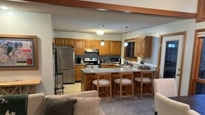 Un espacio habitable compacto con kitchenette, comedor y zona de estar con sofá y sillas.