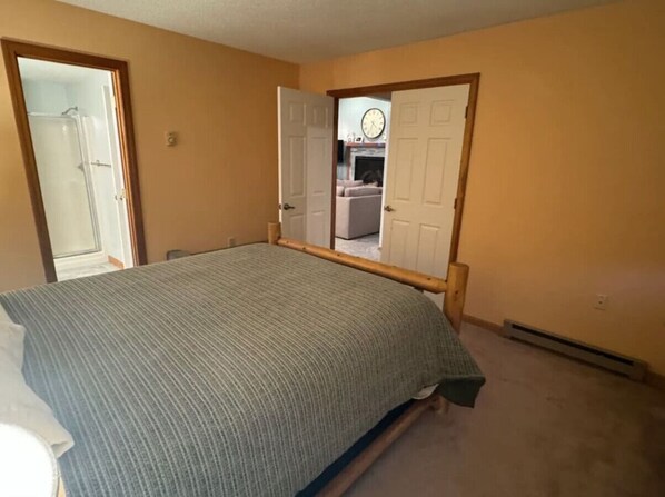 Un dormitorio con cama, dos puertas y un baño visible.