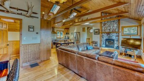A cozy interior with a stone fireplace, wooden beams, and a leather sofa. - Private River Access & Mtn Views (Woodstock)