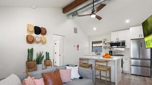 A modern kitchen with stainless steel appliances, a dining area with wooden chairs, and a grey sofa with multiple cushions. - Complex | Theater, Pickleball & Pool in DT Phoenix (Phoenix)
