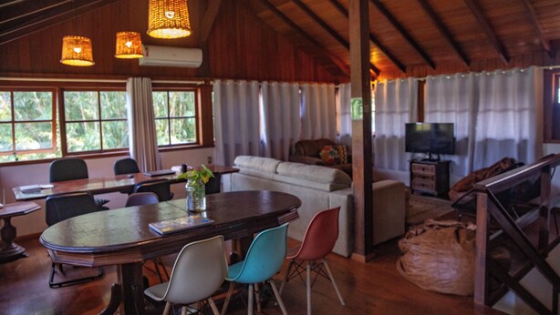 Un'ampia stanza con soffitto in legno, un'area pranzo con tavolo e sedie, un divano e un televisore.