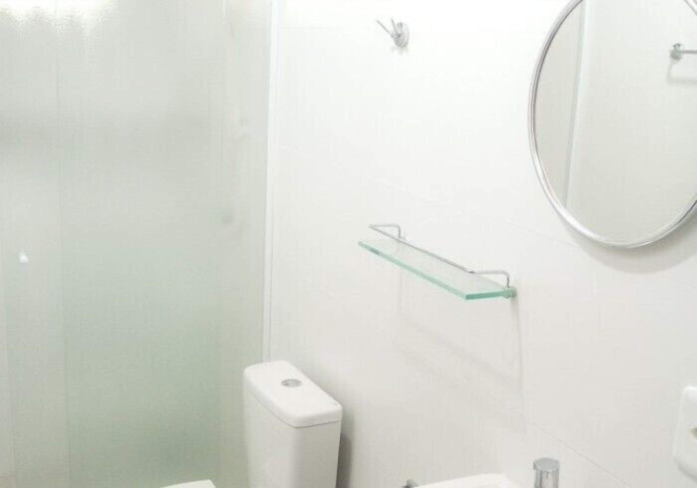 Een badkamer met een glazen plank, een toilet en een spiegel.