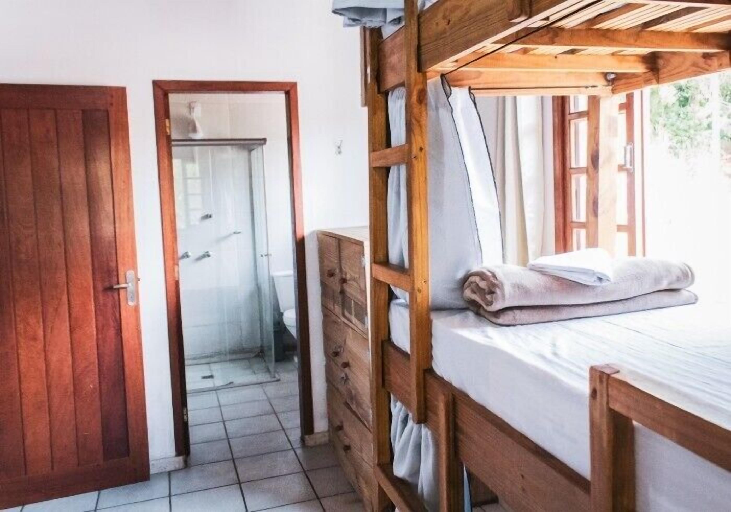 A room with a wooden bunk bed, a wooden wardrobe, and a door leading to a bathroom.