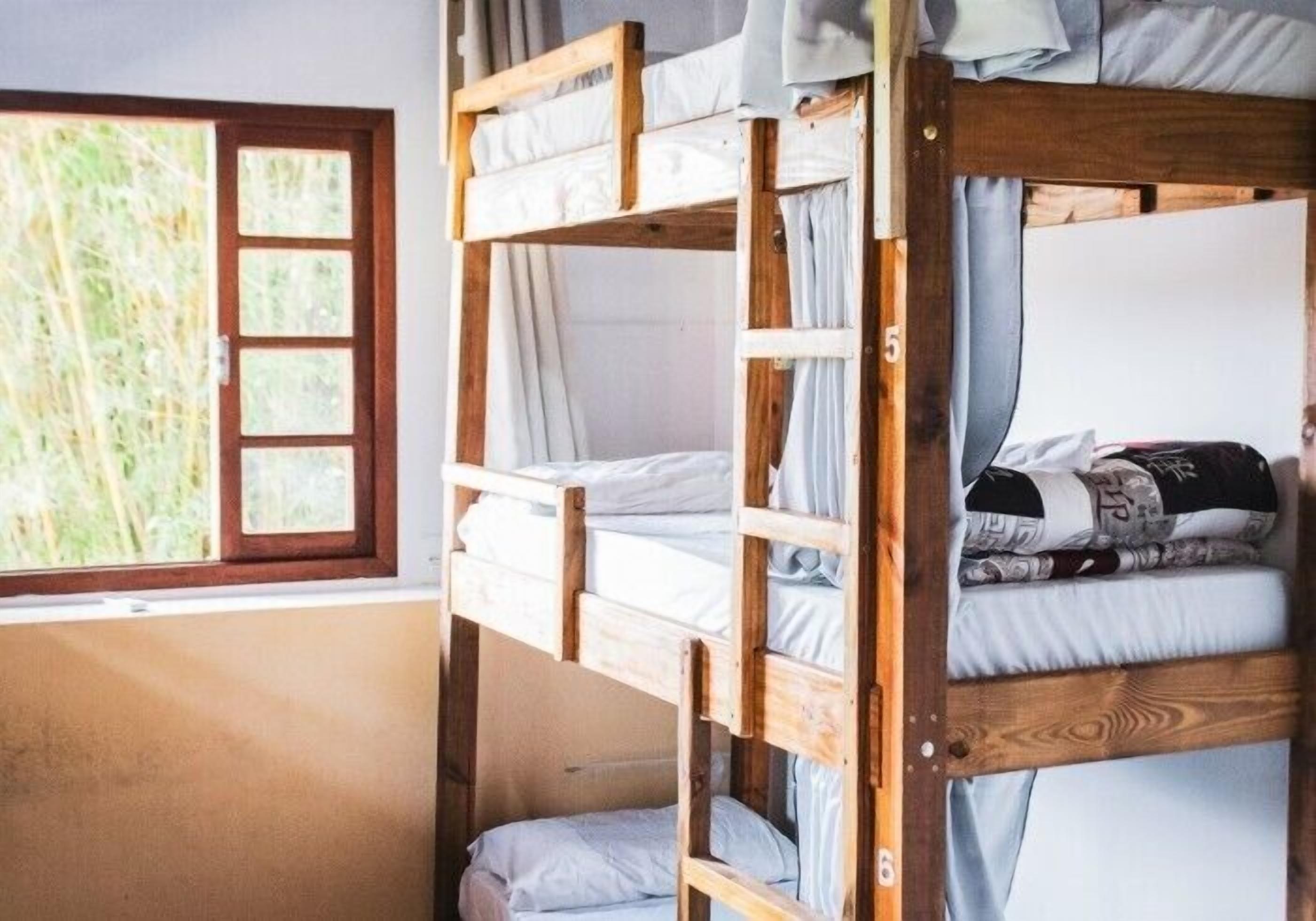 Ein Schlafraum mit Etagenbett, Fenster, Holzrahmen und weißer Bettwäsche.