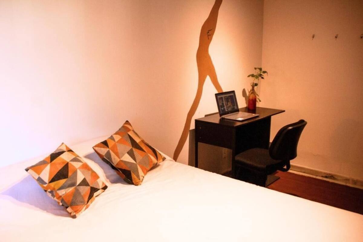 Une chambre d’hôtel avec un lit, un bureau avec un ordinateur portable et une chaise.