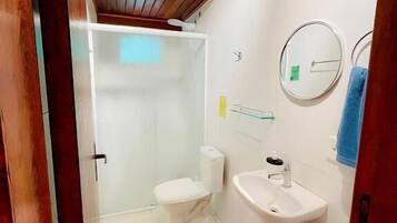 A bathroom with a shower, toilet, sink, and a mirror.