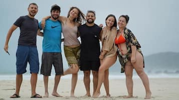 Un grupo de personas de pie en una playa con cielo nublado al fondo.