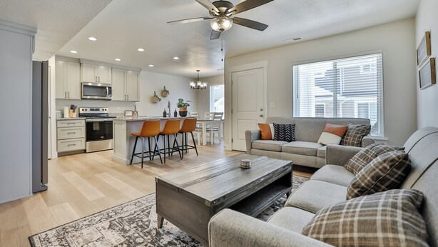 A spacious living room with a sofa, coffee table, and a dining area with chairs and a kitchen in the background.
