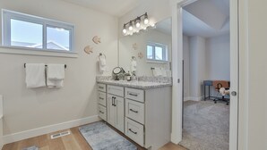 A bathroom with a vanity, a mirror, and a shower area.
