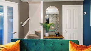 Un salon avec un canapé vert, une table basse et un miroir au mur.